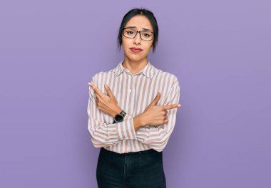 Gündelik kıyafetler giyen ve gözlüklü genç İspanyol kız her iki tarafı da parmaklarıyla işaret ediyor, farklı yönlere. 