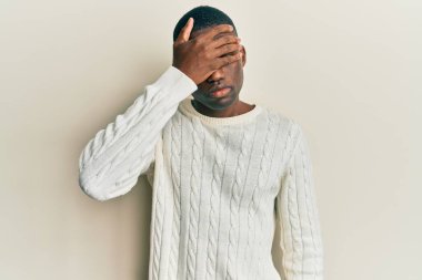 Genç, Afro-Amerikan bir adam, günlük kıyafetler giyip, elleriyle gözlerini kapatıyor, ciddi ve üzgün görünüyor. Görme, saklama ve reddetme konsepti 