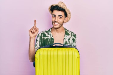 Yaz stili giyinmiş genç İspanyol bir adam ve elinde bir fikir veya soruyla gülümseyen bir kamara çantası var. 