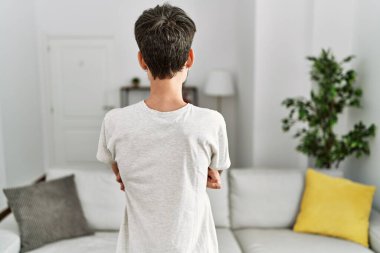 Oturma odasında sakallı İspanyol bir adam kollarını kavuşturup arkasını kolluyor. 