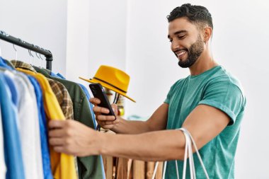 Genç Arap müşteri elbise mağazasından kıyafet alışverişine resim yapıyor.