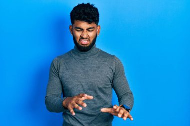 Balıkçı yaka kazak giyen, sakallı Arap adam tiksindirici bir ifade takınıyor ve tiksindirici bir yüz ifadesi takınıyor.. 