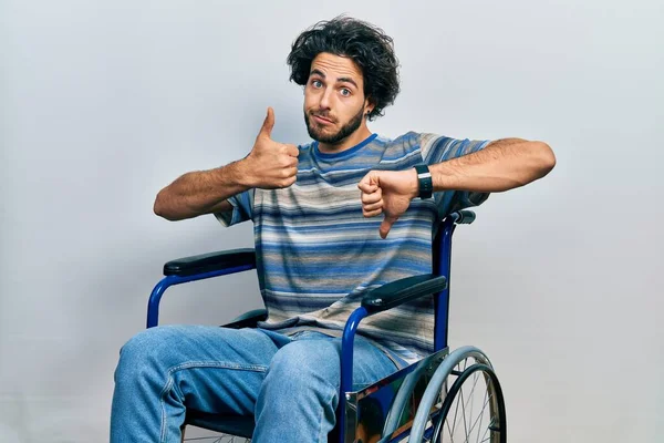 Handsome Hispanic Man Sitting Wheelchair Doing Thumbs Disagreement Agreement Expression — Stock Photo, Image