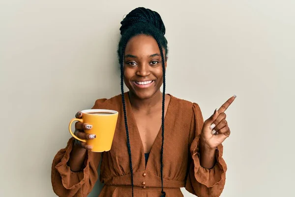 Αφροαμερικανή Γυναίκα Πλεγμένα Μαλλιά Πίνοντας Καφέ Χαμογελώντας Χαρούμενη Δείχνοντας Χέρι — Φωτογραφία Αρχείου
