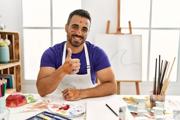 年轻的他的恐慌男子 胡子在艺术工作室与画的脸做快乐的大拇指举手表决手势 赞成的表情看着相机显示的成功 — 图库照片
