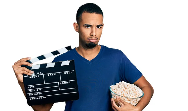 Giovane Uomo Afroamericano Mangiare Popcorn Tenendo Pellicola Clapboard Depresso Preoccuparsi — Foto Stock