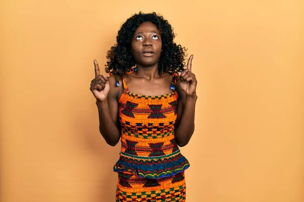 Young African American Woman Wearing Traditional African Clothes Amazed Surprised — стокове фото