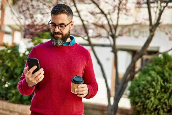 Young hispanic executive man using smartphone and drinking coffee at the city.