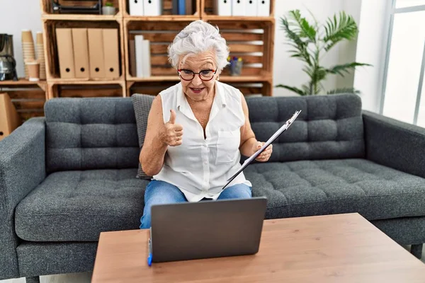在咨询处工作的白发老年妇女做在线治疗时 面带微笑 面带微笑 大拇指向上做得出色 并签了字 — 图库照片