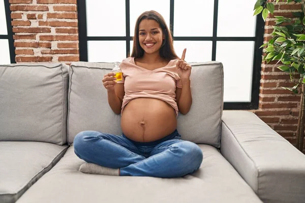 Mujer Embarazada Joven Sosteniendo Aceite Hidratante Para Hidratar Vientre Sonriendo — Foto de Stock