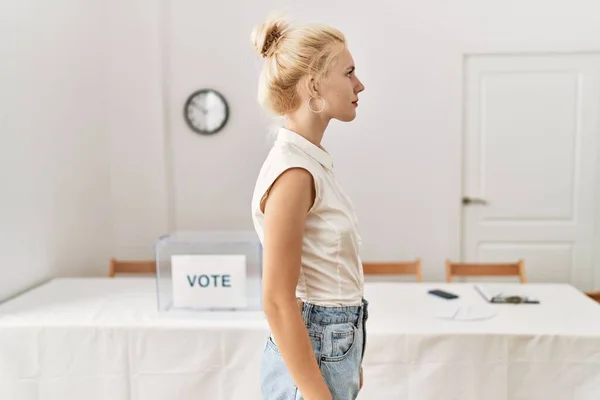 側を探して選挙室で投票することによって立って美しい白人女性 自信を持って笑顔で自然な顔でプロファイルのポーズをリラックス — ストック写真