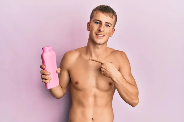Young Caucasian Man Shirtless Holding Shampoo Bottle Smiling Happy Pointing — Zdjęcie stockowe