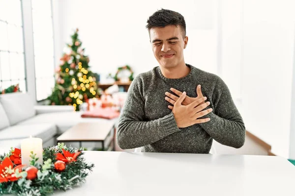 Молодий Іспаномовний Чоловік Сидить Столі Різдвяною Ялинкою Посміхаючись Руками Грудях — стокове фото