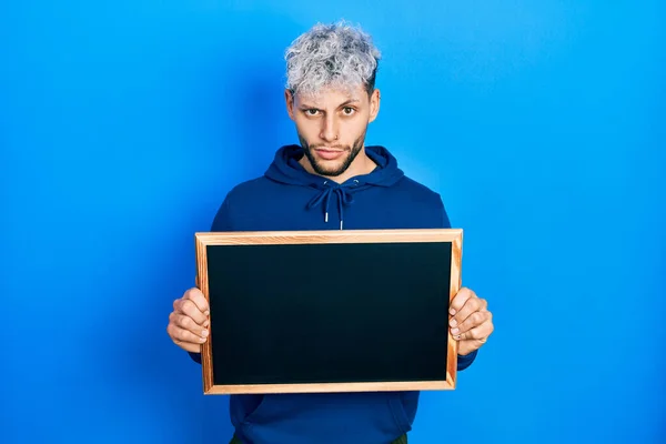 Young Hispanic Man Modern Dyed Hair Holding Blackboard Skeptic Nervous — Stockfoto