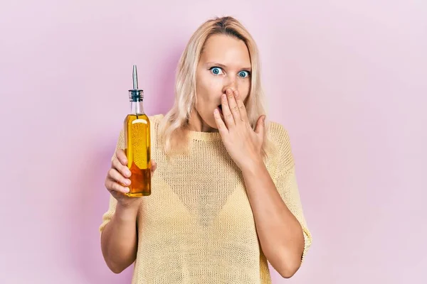 Beautiful Caucasian Blonde Woman Holding Olive Oil Bottle Covering Mouth — Fotografia de Stock