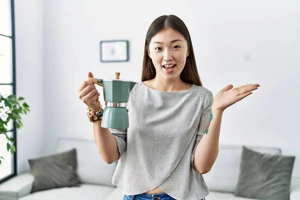 Young Asian Woman Holding Italian Coffee Maker Celebrating Achievement Happy — Stockfoto
