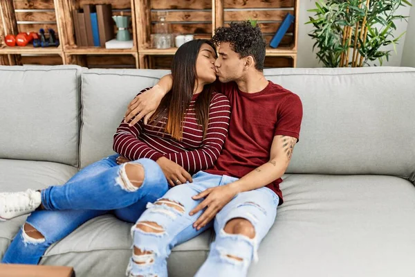 Young Latin Couple Kissing Hugging Sitting Sofa Home — Stockfoto