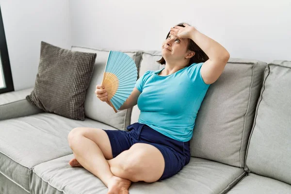 Donna Bruna Con Sindrome Seduta Sul Divano Con Ventilatore Mano — Foto Stock
