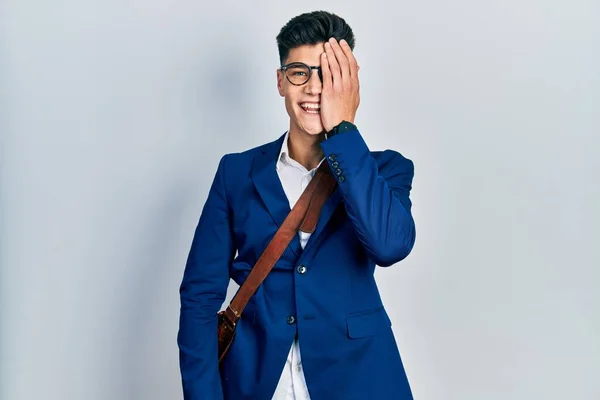 顔に自信のある笑顔と驚きの感情で一つの目を覆うビジネス服を着ている若いヒスパニック系の男 — ストック写真