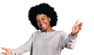 Gündelik giysiler giymiş genç Afro-Amerikan kadın kameraya sarılıp gülümseyerek bakıyor. Mutluluğu kucaklayan neşeli bir ifade.. 
