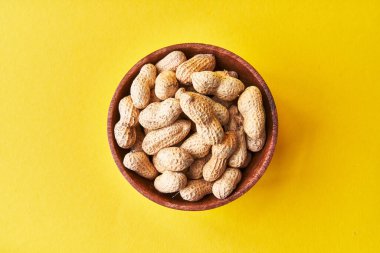  Sarı arka planda kabuklu fıstık kasesi.