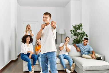 Bir grup genç arkadaş evde mikrofon kullanarak şarkı söylüyor..