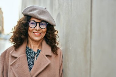 Orta yaşlı İspanyol kadın gülümseyerek şehirde mutlu mesut dikiliyor..