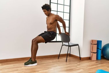 Genç Afrikalı Amerikalı adam spor salonunda şınav çekiyor.