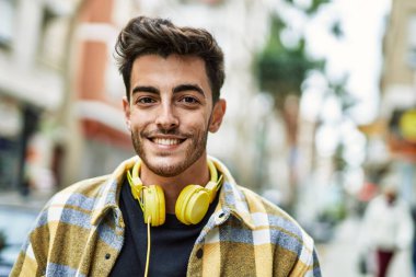 Yakışıklı İspanyol adam, mutlu ve kendine güvenen, kulaklık takan, modern tarzda gülümseyen.