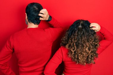 Orta yaşlı bir çift İspanyol kadın ve erkek el ele tutuşup şüpheyi düşünerek sarılıp yan yana duruyorlar. 