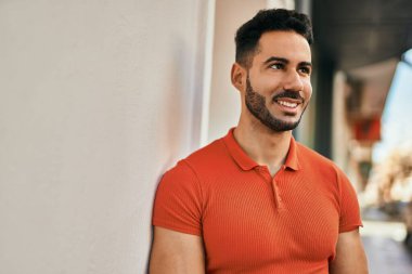 Genç İspanyol adam gülümseyerek şehirde mutlu mesut dikiliyor..