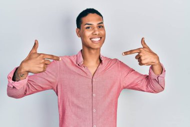 Genç, Afro-Amerikalı, günlük kıyafetler giyen, kendine güvenen, gülümseyen, kendini gururlu ve mutlu gösteren bir adam.. 