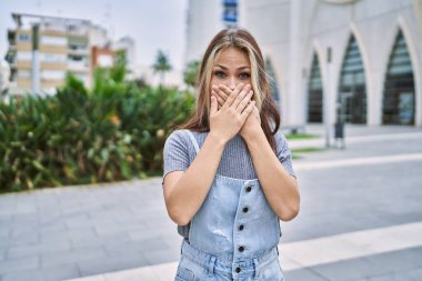 Young caucasian woman outdoors shocked covering mouth with hands for mistake. secret concept. 
