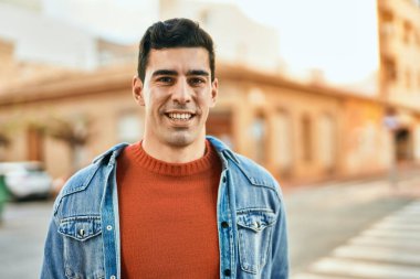 Genç İspanyol adam gülümseyerek şehirde mutlu mesut dikiliyor..