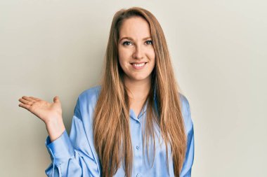 Genç, mavi gömlekli, neşeli bir şekilde gülümseyen, avuç içi kameraya bakan sarışın bir kadın.. 