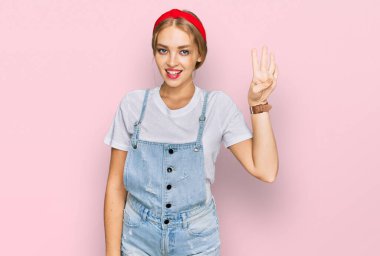 Gündelik giysiler giymiş genç beyaz bir kız dört numarayı gösterip işaret ederken kendinden emin ve mutlu bir şekilde gülümsüyor.. 