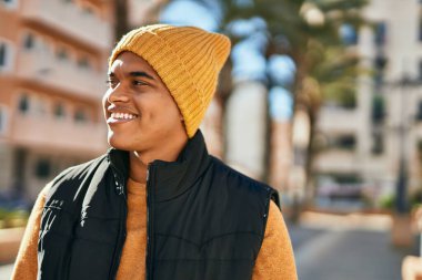 Genç Latin adam gülümseyerek şehirde mutlu mesut dikiliyor.