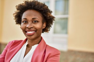 Güzel bir iş adamı Afro saçlı Amerikalı kadın şehirde mutlu ve kendinden emin bir şekilde gülümsüyor.