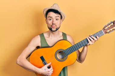 Latin asıllı genç bir adam klasik gitar çalıyor. Kameraya bakıyor. Öpücük atıyor. aşk ifadesi. 