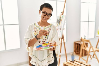 Genç İspanyol kadın resim stüdyosunda kendine güvenen gülümsüyor.