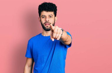 Mavi tişörtlü, sakallı genç Arap adam kameraya kızgın ve sinirli bir şekilde kızgın olduğunu gösteriyor. 