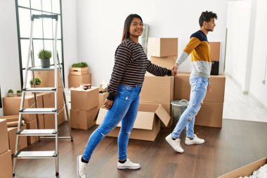 Yeni evimizde el ele tutuşup mutlu gülümseyen genç Latin çift..