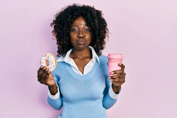 Młoda Afroamerykanka Jedząca Pączki Pijąca Kawę Nadymającą Policzki Śmieszną Twarzą — Zdjęcie stockowe