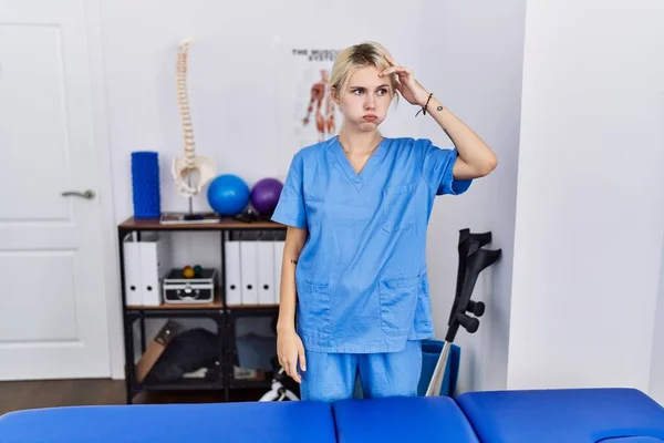 痛みの回復クリニックで働いている若い理学療法士の女性が心配し 額に手で問題について強調しました 危機への神経と不安 — ストック写真