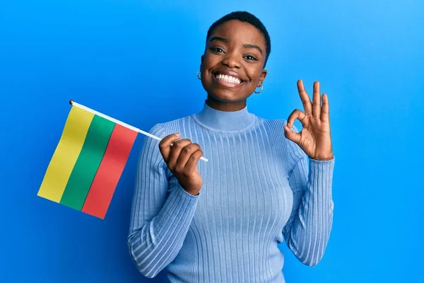 Young African American Woman Holding Lithuania Flag Doing Sign Fingers — стоковое фото