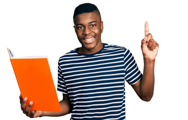 Young African American Man Holding Book Surprised Idea Question Pointing — Stock Photo, Image