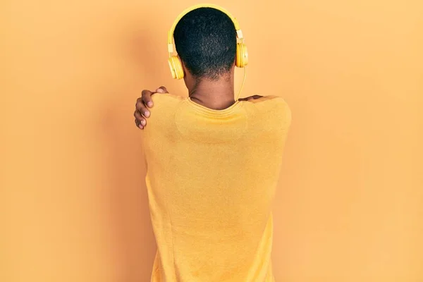 Young African American Guy Listening Music Using Headphones Hugging Oneself — Stockfoto