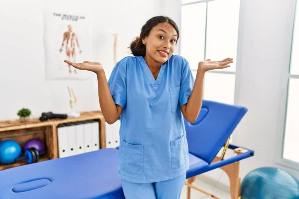 Beautiful Hispanic Physiotherapist Woman Pain Recovery Clinic Clueless Confused Expression — Stockfoto