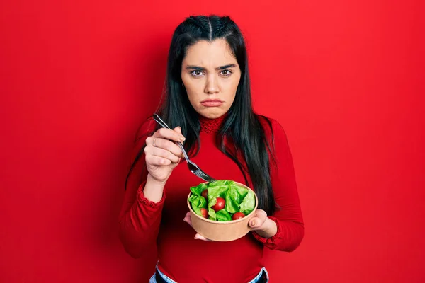 年轻的惊慌失措的女孩吃沙拉时充满怀疑和紧张 皱着眉头因问题而心烦意乱 消极的人 — 图库照片