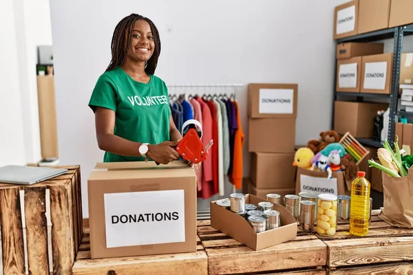 Young African American Woman Wearing Volunteer Uniform Packing Donations Box — Stock Photo, Image